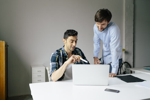 Zwei Geschäftsleute mit Laptop am Schreibtisch im Büro diskutieren - BMF00852