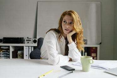 Junge Frau mit einer Tasse Kaffee am Schreibtisch im Büro - BMF00865