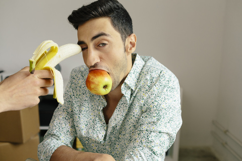 Portrait of casual businessman with banana at temple and apple in mouth stock photo