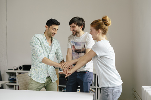 Happy colleagues in office stacking hands stock photo