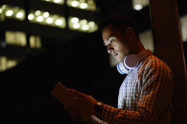 Portrait of young man in the city using tablet at night - JRFF01479