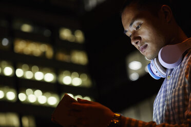 Porträt eines jungen Mannes in der Stadt bei der Verwendung eines Tablets in der Nacht - JRFF01480