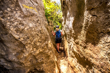 Spain, Malaga Province, El Torcal, woman hiking through gorge - SMAF00868