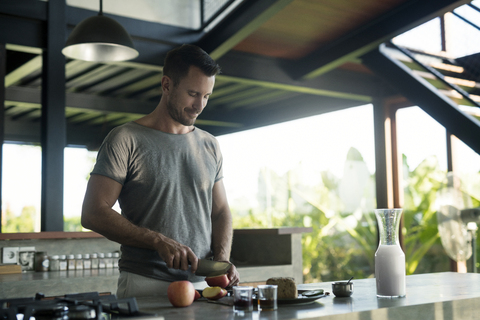 Man preparing breakdast with milk, bread and fruit stock photo