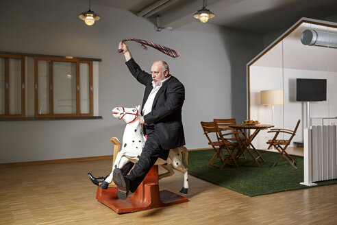Businessman on rocking horse pretending to ride - PESF00750