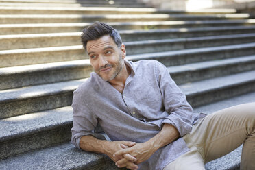 Portrait of smiling mature man sitting on stairs - PNEF00309