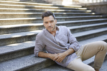 Portrait of serious mature man sitting on stairs - PNEF00311