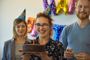 Colleagues having a birthday celebration in office with cake and party hats - ZEDF00979