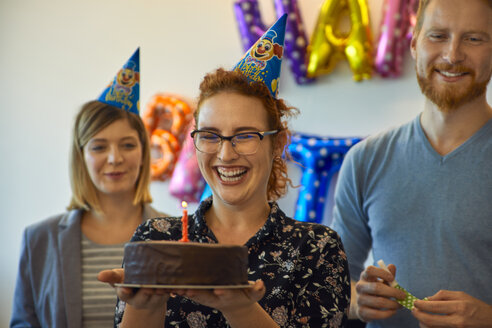 Kollegen feiern Geburtstag im Büro mit Kuchen und Partyhüten - ZEDF00979