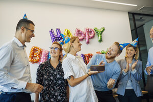Kollegen feiern Geburtstag im Büro mit Kuchen und Partyhüten - ZEDF00984
