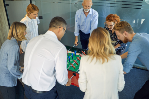 Kollegen spielen Tischfußball im Büro, lizenzfreies Stockfoto