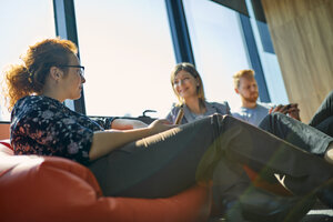 Kollegen sitzen in Sitzsäcken in der Bürolounge - ZEDF00989