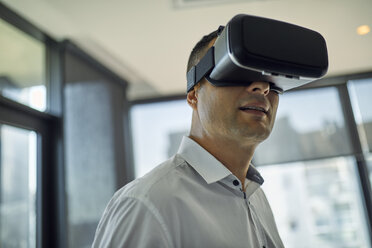 Man wearing VR glasses in office - ZEDF00992