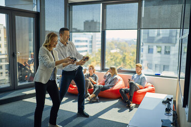 Colleagues playing video game in office - ZEDF00993