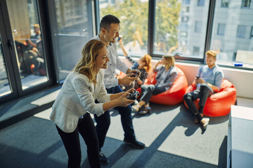 Colleagues playing video game in office - ZEDF00994