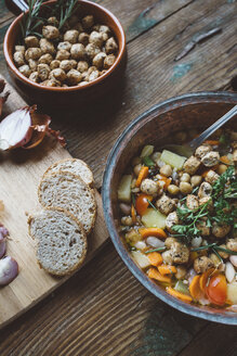 Mediterrane Suppe im Kupfertopf, Schale mit Croutons und Brotscheiben auf Holzbrett - GIOF03292