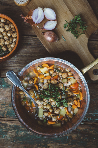 Mediterrane Suppe in Kupfertopf, Schale mit Croutons und Zutaten auf Holzbrett, lizenzfreies Stockfoto