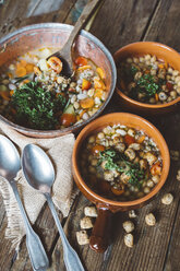 Mediterranean soup in copper pot and terracotta bowls on wood - GIOF03297