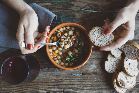 Frau isst mediterrane Suppe mit Brot, Nahaufnahme, lizenzfreies Stockfoto