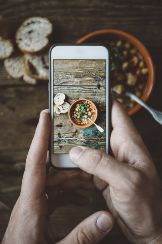 Männerhand beim Fotografieren einer mediterranen Suppe in einer Schüssel, Nahaufnahme, lizenzfreies Stockfoto