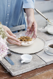 Italy, woman arranging bowl of granola on breakfast table, partial view - ALBF00200