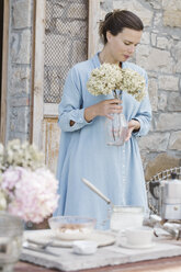 Italien, Frau mit Hortensienblüten in Vase auf Terrasse - ALBF00204