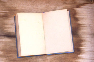 Aufgeschlagenes altes Buch mit leeren Seiten auf Holz - CMF00752