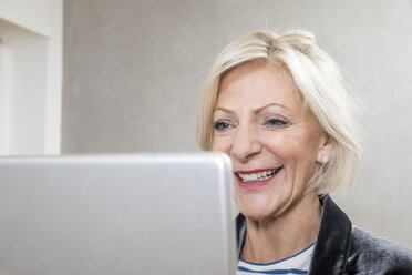 Porträt einer glücklichen älteren Frau, die ein Tablet benutzt - FMKF04619