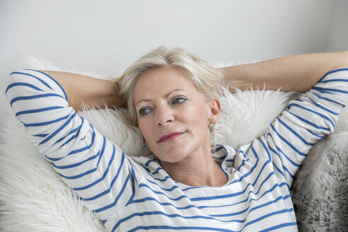 Portrait of senior woman relaxing on couch at home - FMKF04633