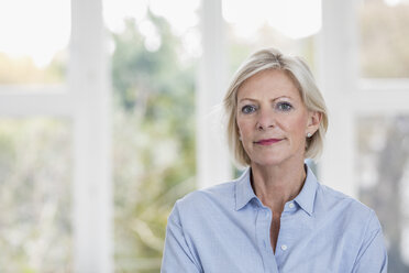 Portrait of smiling senior woman in front of window - FMKF04636