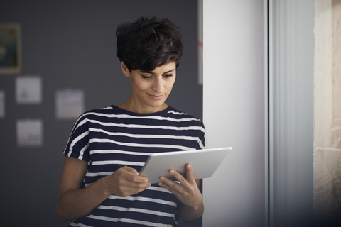 Frau mit Tablet am Fenster, lizenzfreies Stockfoto