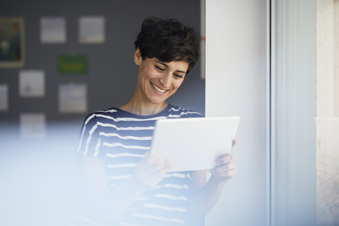 Lächelnde Frau mit Tablet am Fenster - RBF06108