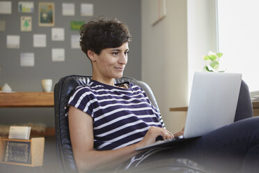 Lächelnde Frau benutzt Laptop zu Hause - RBF06115