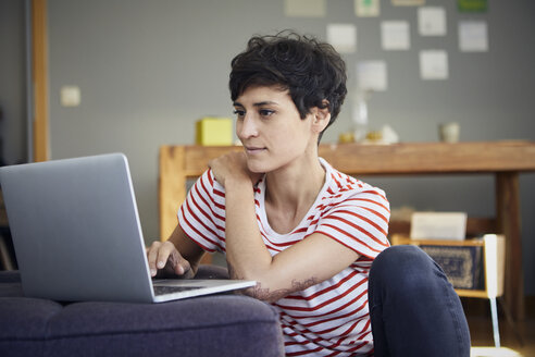 Smiling woman using laptop at home - RBF06123