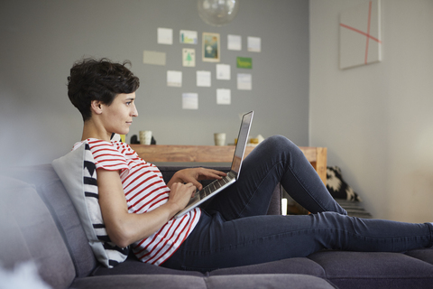 Woman using laptop on couch at home stock photo