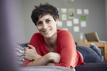 Portrait of smiling woman lying on couch at home - RBF06134