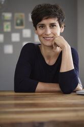 Portrait of smiling woman sitting at table at home - RBF06160