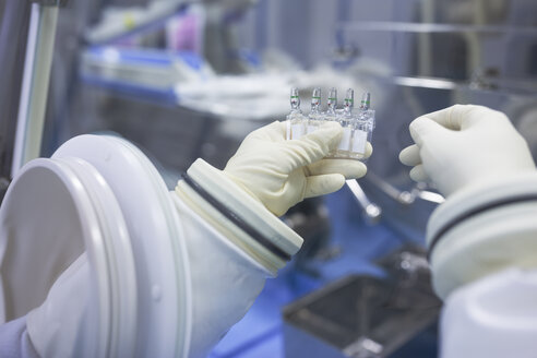 Scientist holding vials in insulator laboratory - WESTF23582