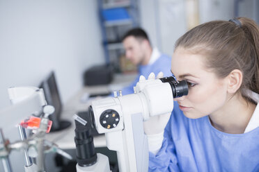 Lab technician looking through microscope - WESTF23619