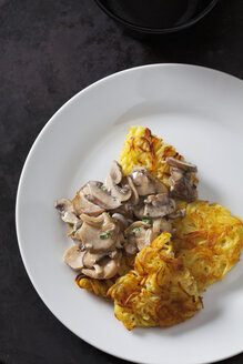 Kartoffelröstis mit Champignons in Sahnesauce auf Teller - CSF28537