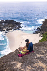 Indonesia, Lombok, couple sitting at the coast looking at view - KNTF00904