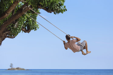 Indonesia, Lombok Island, man sitting on a swing looking at distance - KNTF00905