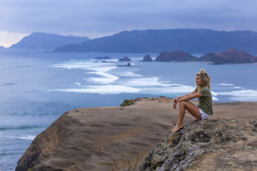 Indonesien, Lombok, Frau sitzt an der Küste und betrachtet die Aussicht - KNTF00908