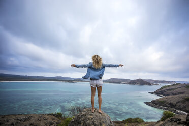 Indonesia, Lombok, woman standing at the coast with outstretched arms - KNTF00911