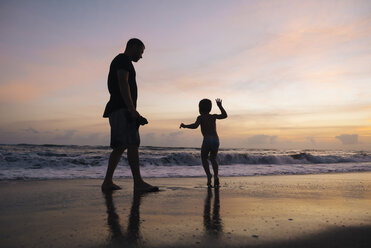 Indonesien, Bali, Vater und Sohn am Strand bei Sonnenuntergang - KNTF00916