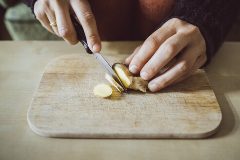 Woman's hands cutting ginger on wooden board, close-up - JSCF00011