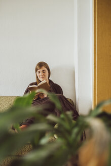 Frau sitzt auf der Couch im Wohnzimmer und liest ein Buch - JSCF00016