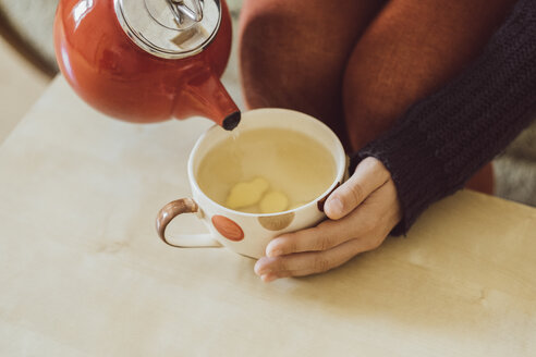 Frau gießt Wasser in Teetasse mit gehacktem frischem Ingwer, Nahaufnahme - JSCF00023