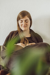 Smiling woman sitting on couch writing in notebook - JSCF00025