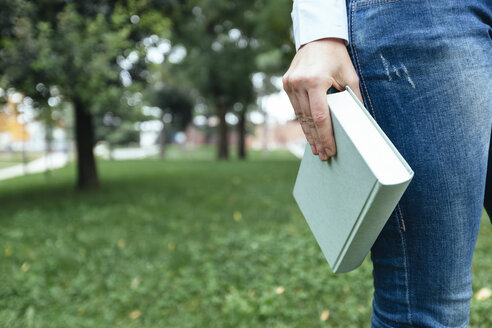 Mädchen geht im Park spazieren, trägt ein Buch, Nahaufnahme - GIOF03314
